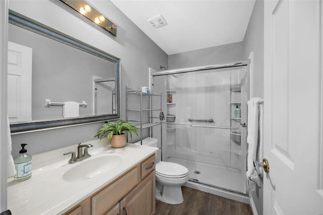 bathroom featuring hardwood / wood-style floors, toilet, a shower with door, and vanity