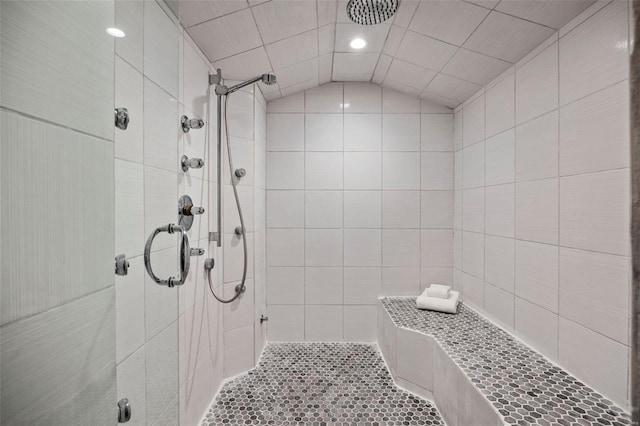 bathroom with vaulted ceiling, a shower with shower door, and tile walls