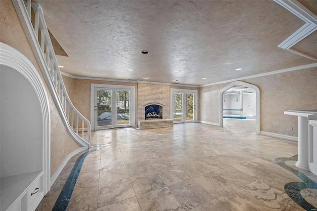 unfurnished living room with crown molding, french doors, and a fireplace