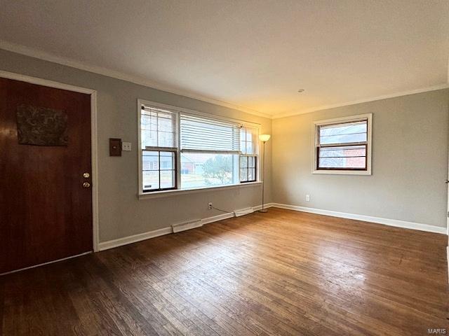 empty room with a healthy amount of sunlight, ornamental molding, and dark wood-type flooring