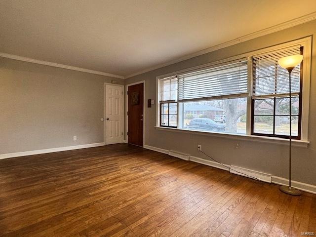 spare room with plenty of natural light, ornamental molding, and dark wood-type flooring