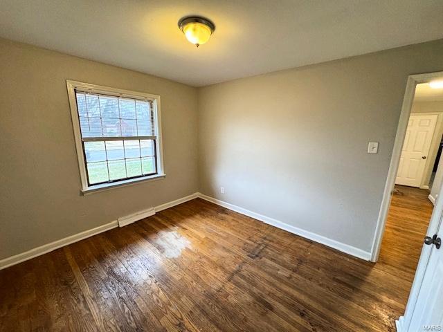 unfurnished room with dark hardwood / wood-style flooring