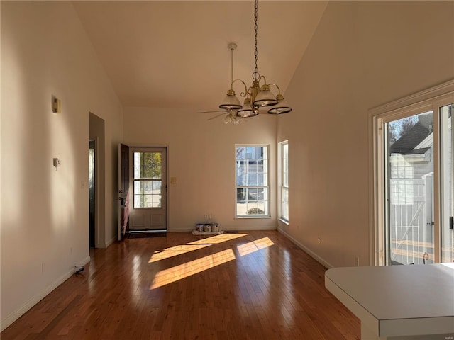 unfurnished dining area with dark hardwood / wood-style flooring, high vaulted ceiling, and a chandelier