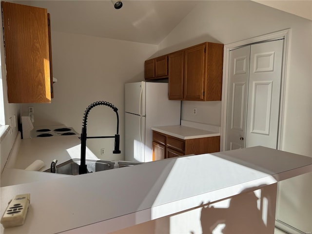 kitchen with white refrigerator, vaulted ceiling, and sink