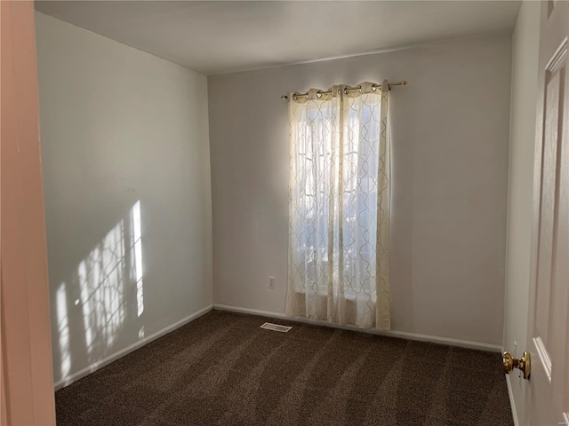 unfurnished room featuring dark colored carpet