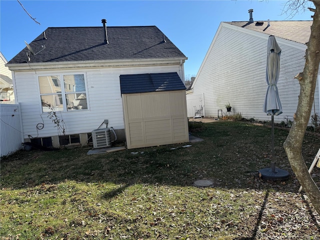 back of property with a lawn, central AC unit, and a shed