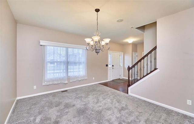 carpeted foyer entrance featuring an inviting chandelier