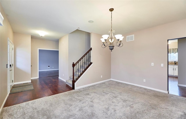 carpeted empty room featuring a chandelier