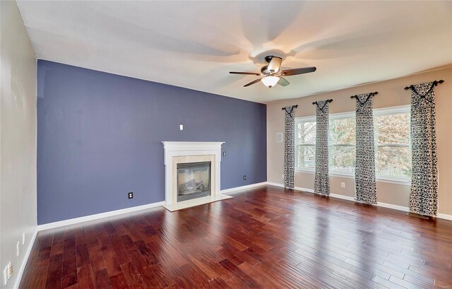 unfurnished living room featuring ceiling fan, a fireplace, and dark wood-type flooring