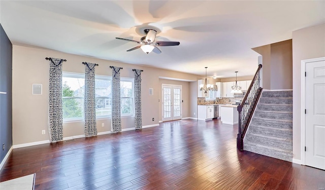 unfurnished living room with dark hardwood / wood-style flooring and ceiling fan with notable chandelier