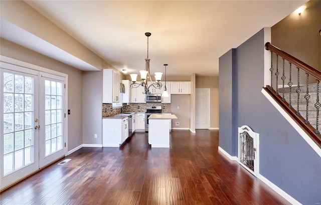 kitchen featuring appliances with stainless steel finishes, backsplash, sink, pendant lighting, and white cabinetry