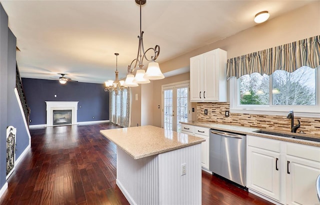 kitchen featuring a center island, sink, hanging light fixtures, stainless steel dishwasher, and white cabinets