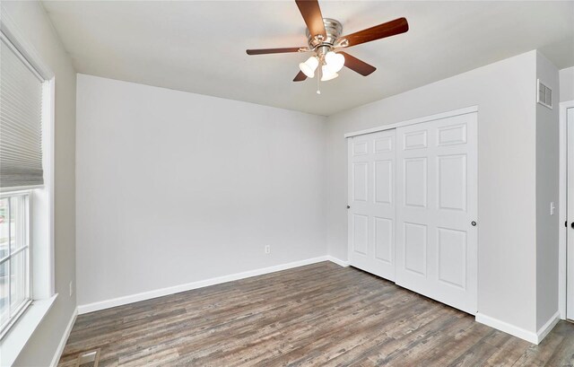 unfurnished bedroom with ceiling fan, dark hardwood / wood-style flooring, and a closet