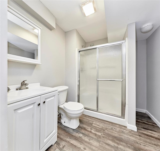 bathroom featuring hardwood / wood-style flooring, vanity, toilet, and a shower with door