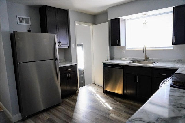 kitchen with light stone countertops, sink, stainless steel appliances, dark hardwood / wood-style floors, and decorative light fixtures