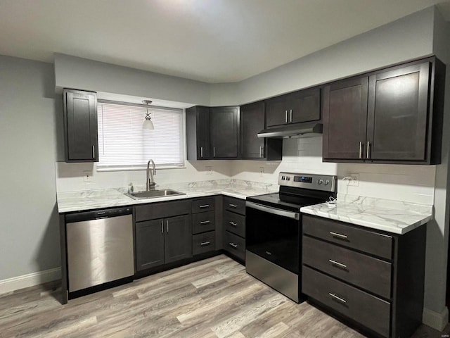 kitchen with sink, light hardwood / wood-style flooring, decorative light fixtures, light stone counters, and stainless steel appliances