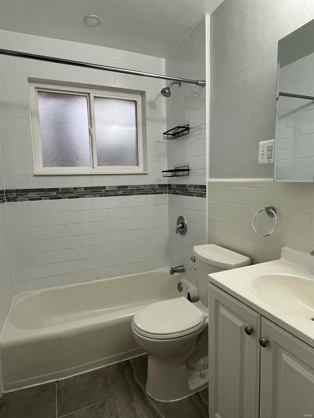 full bathroom featuring vanity, toilet, tile walls, and tiled shower / bath combo