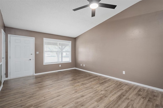 spare room featuring ceiling fan, light hardwood / wood-style floors, and vaulted ceiling