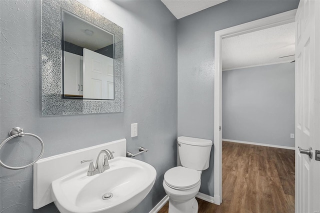 bathroom with toilet, sink, a textured ceiling, and hardwood / wood-style flooring