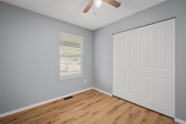 unfurnished bedroom with a textured ceiling, a closet, ceiling fan, and light hardwood / wood-style floors