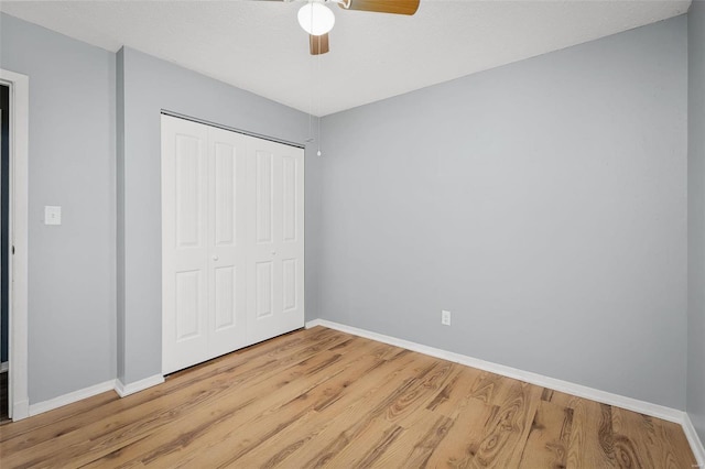 unfurnished bedroom with ceiling fan, light hardwood / wood-style floors, and a closet