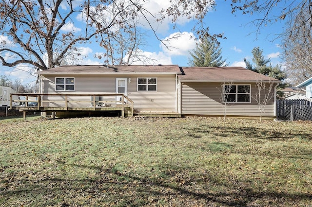 rear view of house with a wooden deck and a lawn