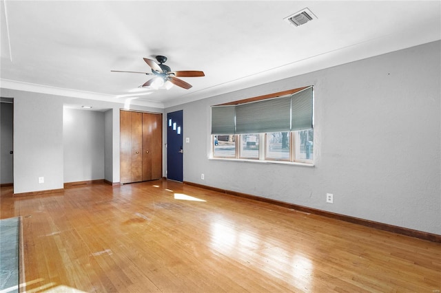 empty room with ceiling fan, ornamental molding, and light wood-type flooring