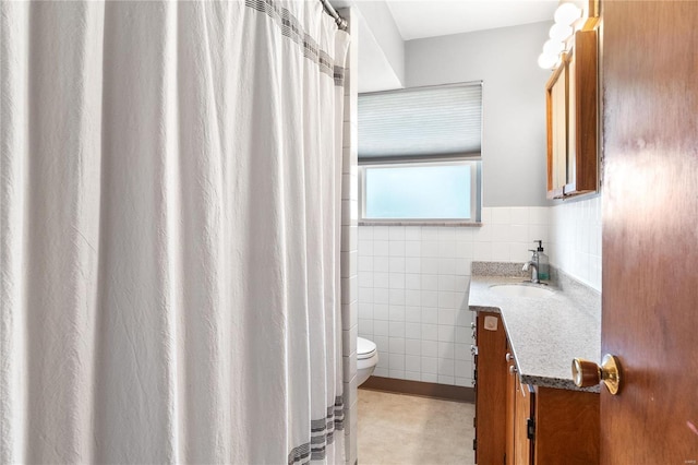 bathroom featuring toilet, vanity, and tile walls