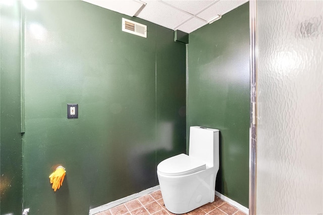 bathroom with toilet, tile patterned floors, and a drop ceiling