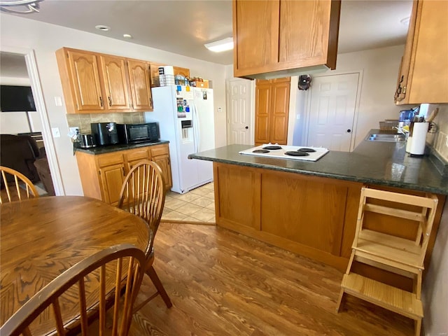 kitchen featuring light wood-type flooring, white appliances, kitchen peninsula, and tasteful backsplash