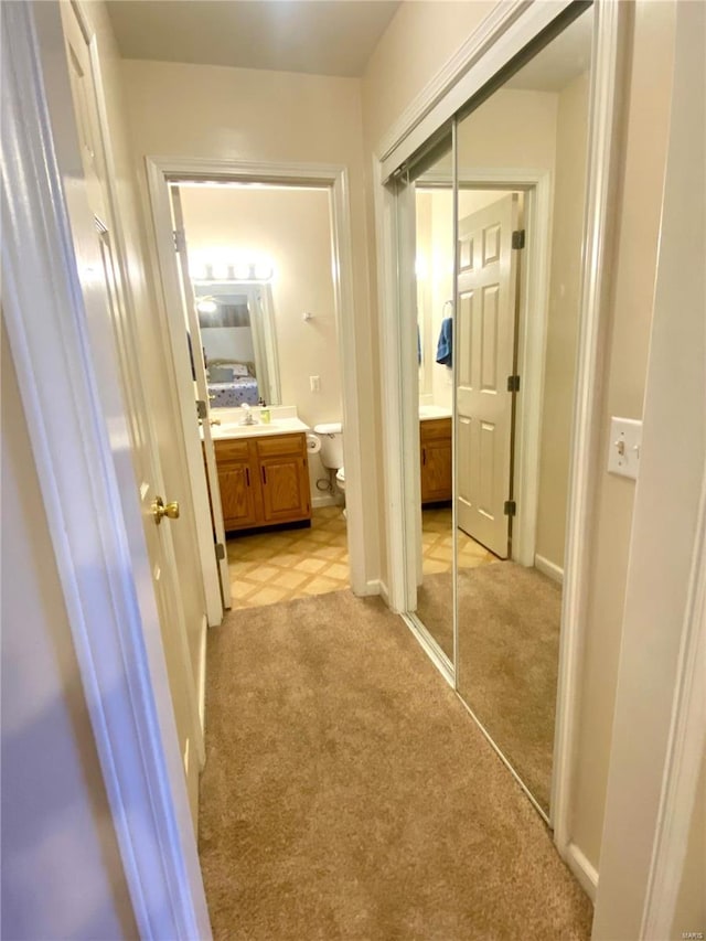 hallway featuring light carpet and sink