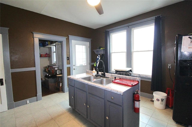 kitchen featuring gray cabinetry, ceiling fan, sink, and a kitchen island with sink