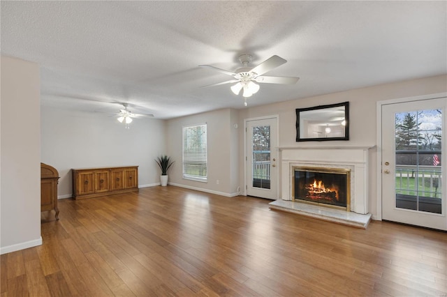 unfurnished living room featuring hardwood / wood-style floors, ceiling fan, and a textured ceiling