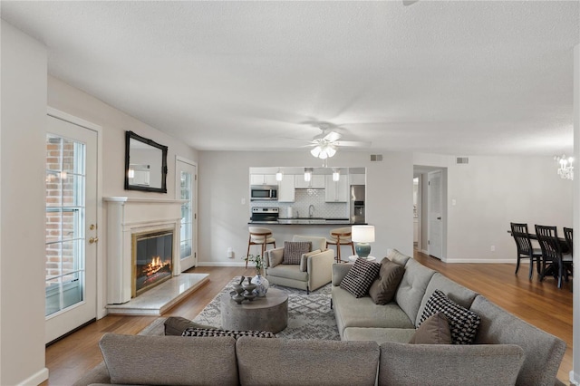 living room featuring a textured ceiling, ceiling fan, light wood-type flooring, and sink