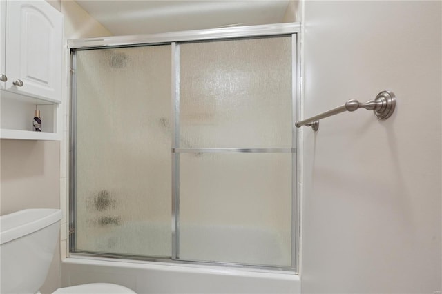 bathroom featuring combined bath / shower with glass door and toilet