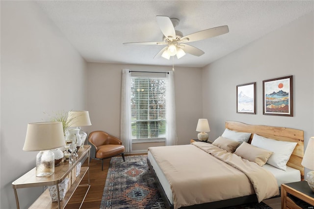 bedroom with ceiling fan, dark wood-type flooring, and a textured ceiling