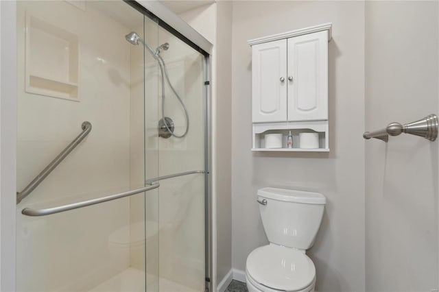 bathroom with a shower with door and toilet