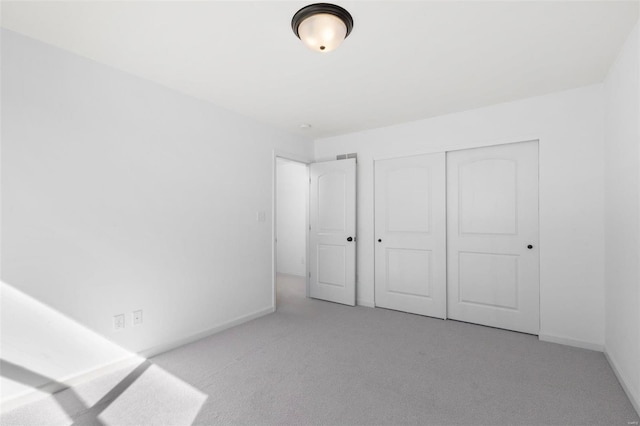 unfurnished bedroom with light colored carpet and a closet