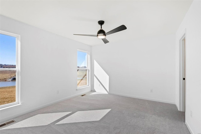 spare room featuring ceiling fan, plenty of natural light, and light colored carpet