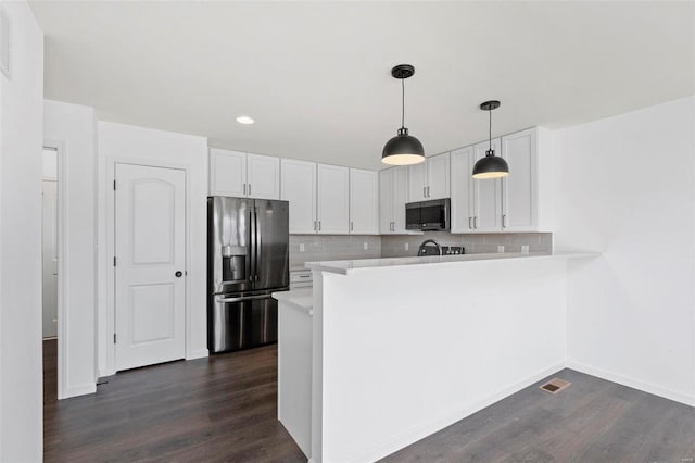 kitchen with kitchen peninsula, stainless steel appliances, white cabinetry, and dark hardwood / wood-style floors