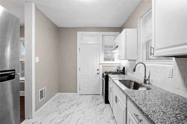 kitchen featuring sink, light stone countertops, tasteful backsplash, white cabinetry, and stainless steel appliances