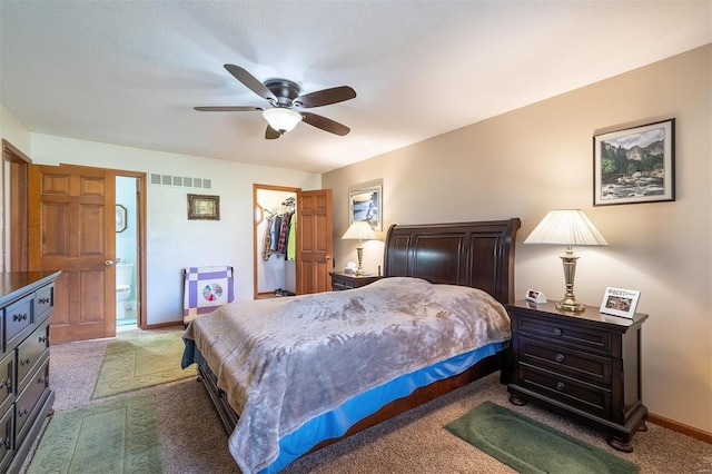 carpeted bedroom featuring ensuite bath, a closet, a spacious closet, and ceiling fan