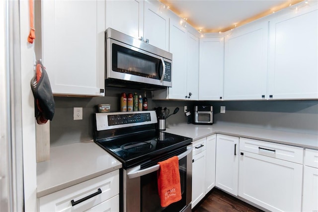 kitchen with dark hardwood / wood-style flooring, white cabinetry, and stainless steel appliances