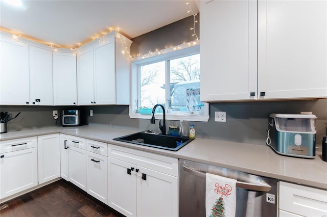 kitchen with dark hardwood / wood-style flooring, sink, white cabinets, and stainless steel dishwasher