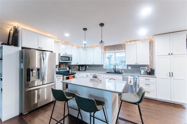 kitchen with a center island, dark wood-type flooring, white cabinets, sink, and stainless steel appliances