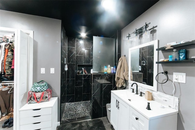 bathroom with tiled shower, vanity, and tile patterned flooring