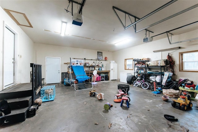 garage featuring a workshop area, white fridge with ice dispenser, and a garage door opener