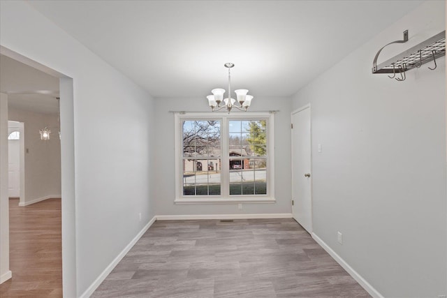 unfurnished dining area with a chandelier and light hardwood / wood-style floors