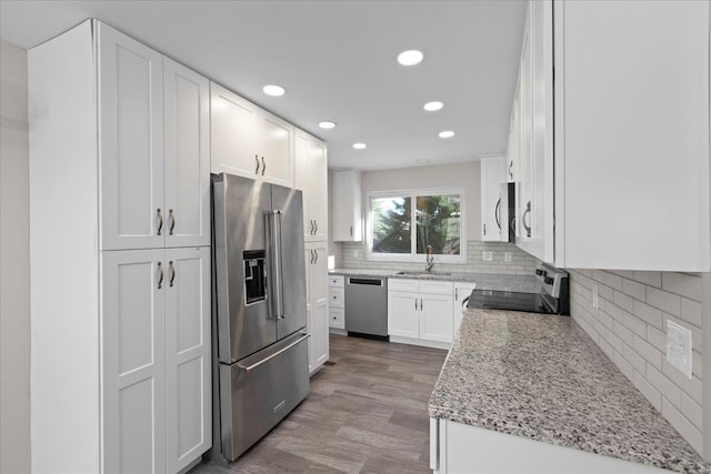 kitchen featuring sink, decorative backsplash, light stone countertops, appliances with stainless steel finishes, and white cabinetry