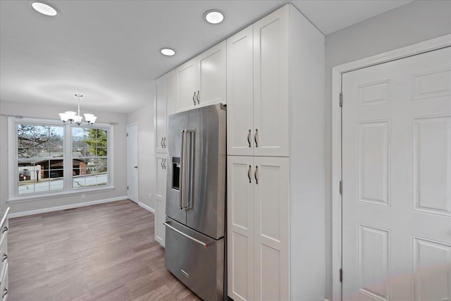 kitchen featuring high end refrigerator, light hardwood / wood-style flooring, a chandelier, pendant lighting, and white cabinets